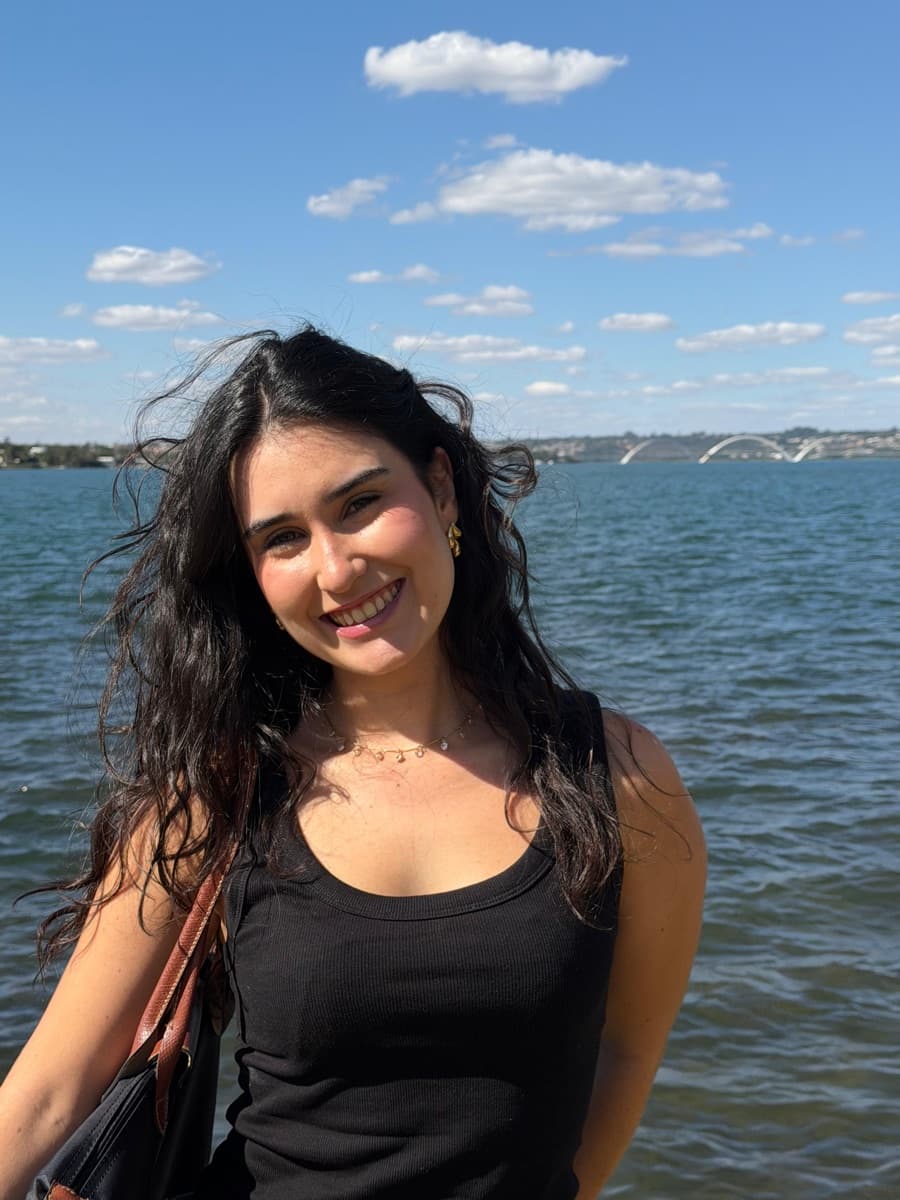 Julia sorrindo em frente ao Lago Paranoá, em Brasília